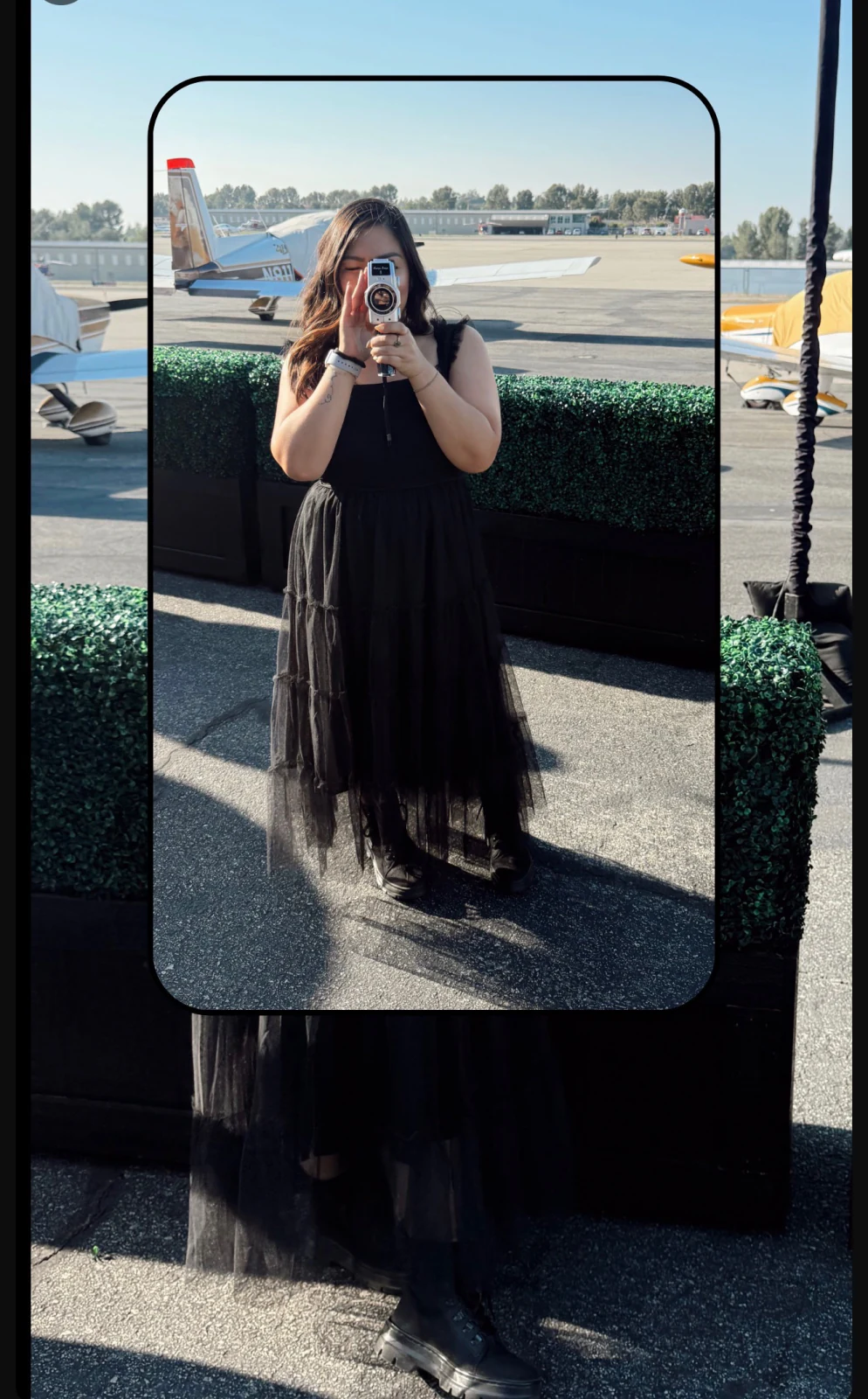 Kat filming with a vintage camera at an airfield
